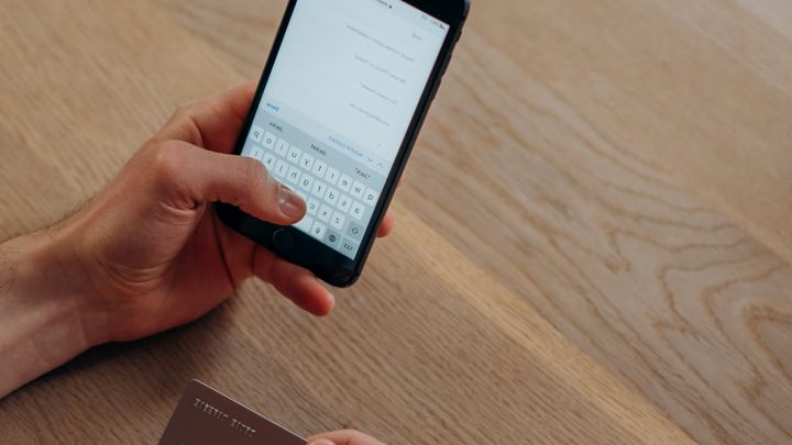 A person holding a phone and making a cashless payment