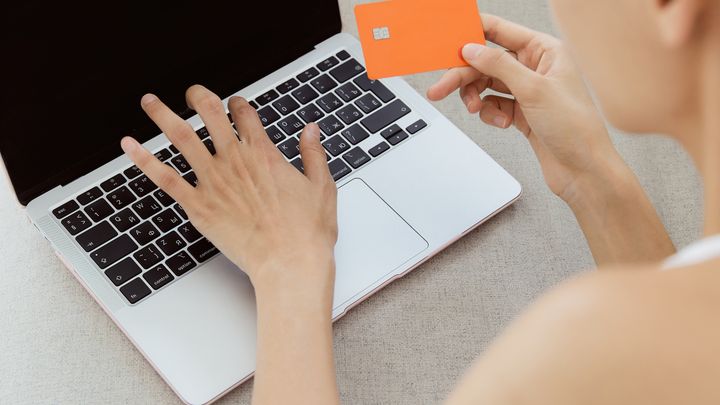 A woman holding a bank card while using a laptop to make an online payment